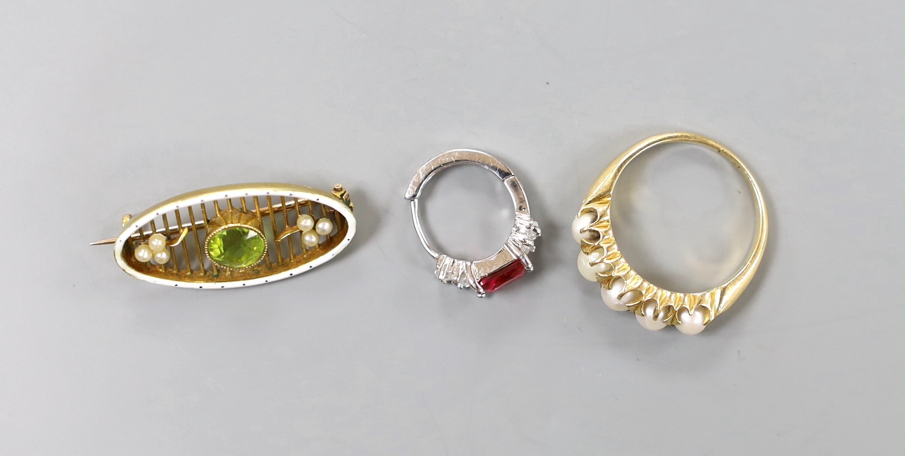 An 18ct and graduated cultured pearl set half hoop ring, size O/P, gross 5.2 grams, an Edwardian yellow metal, enamel, seed pearl and peridot brooch, an amber cig holder and a paste set clip?